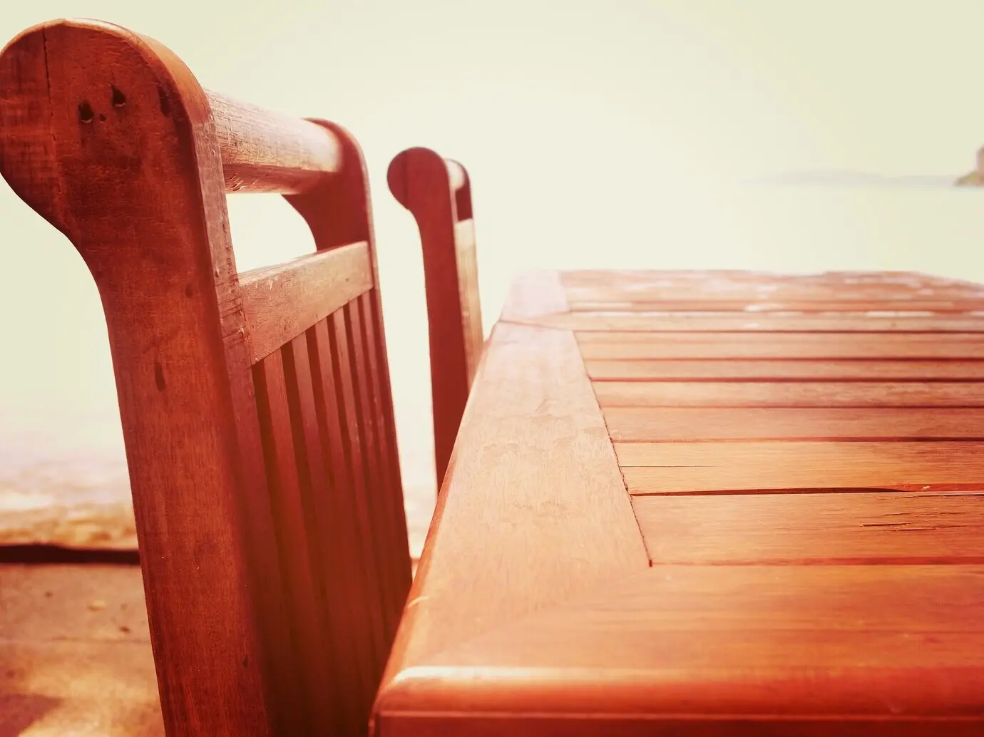 Draußen stehender Tisch mit Strand und Meer im Hintergrund.
